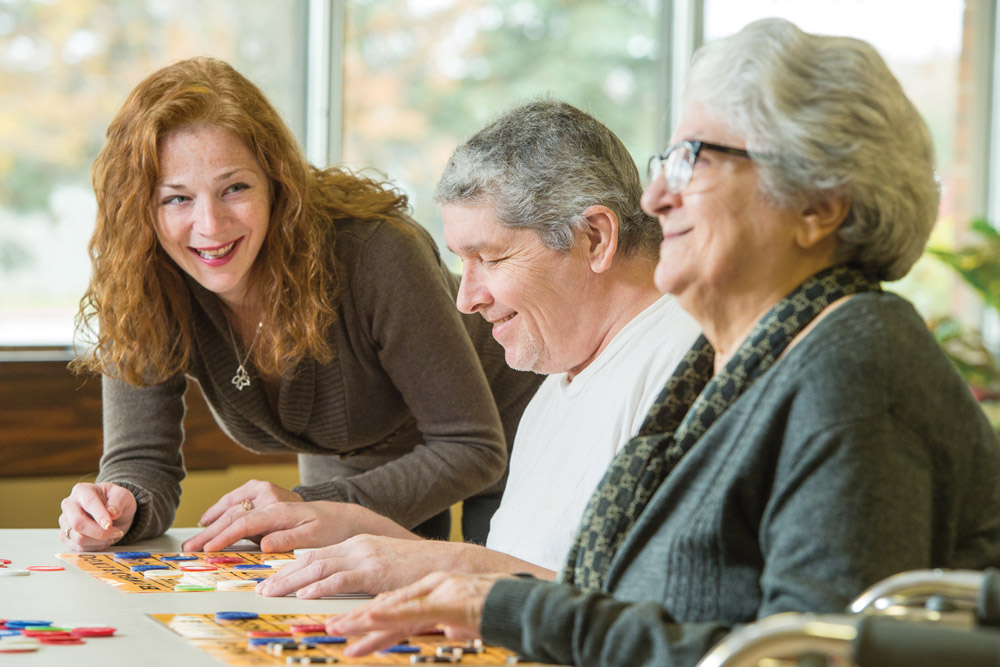 woman checking in on two residents seated at a table